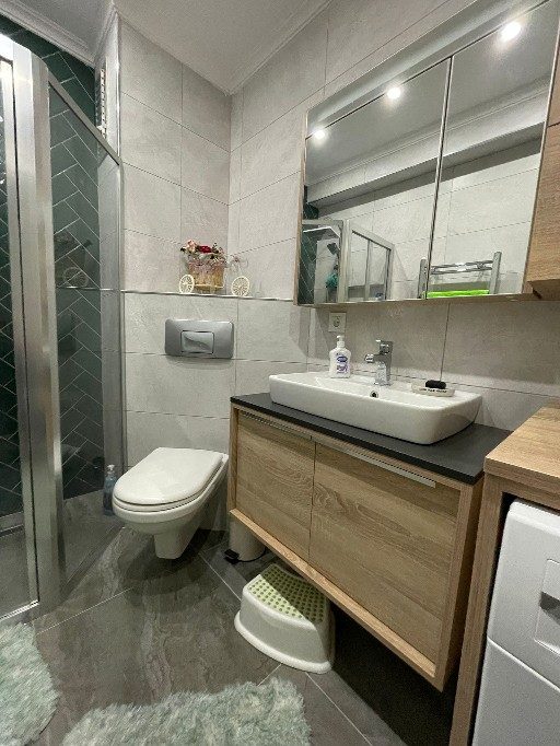 Banyo — yüzer ahşap lavabo ve yeşil balıksırtı duş