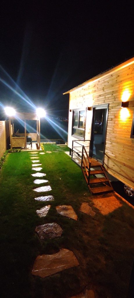 Tekerlekli tiny house — gece aydınlatması ve taş yol